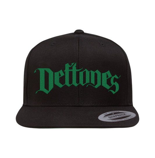 Black metal arch snapback cap with green deftones logo, stitched ventilation eyelets, and plastic snapback size adjuster